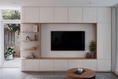 a modern living room with white walls and wooden entertainment center, built in bookshelves