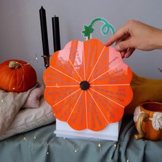 an orange fan sitting on top of a table next to two pumpkins and candles