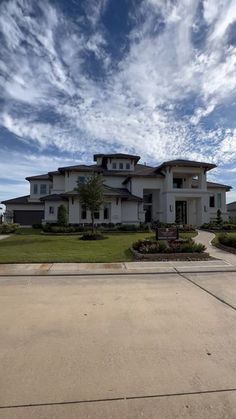 a large white house sitting on top of a lush green field under a blue sky