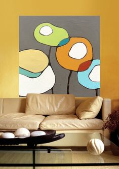 a modern living room with yellow walls and art work on the wall behind the couch