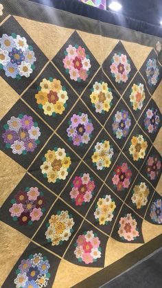 a quilt is displayed on display in a room with lights and flowers hanging from the ceiling