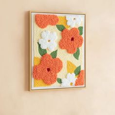 an orange and white wall hanging with flowers on it