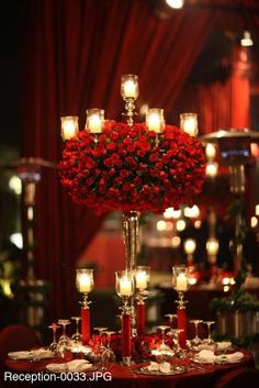 a centerpiece with candles and roses on it