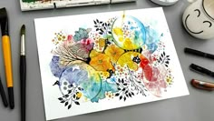 an art work with watercolors and paintbrushes on the table next to it