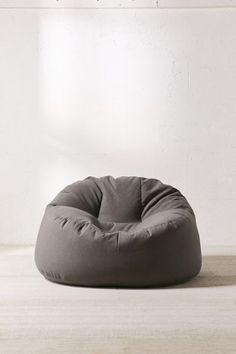 a grey bean bag chair sitting on top of a wooden floor next to a white wall