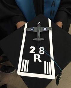 a model airplane on top of a black graduation cap that reads 28 r / m