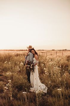 a bride and groom standing in a field with wildflowers