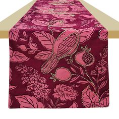 a long table covered in pink and purple flowers with a bird on it's back