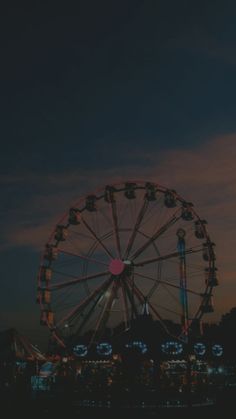 the ferris wheel is lit up at night with bright lights in the sky behind it