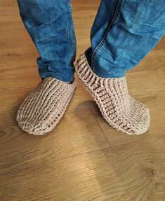 a person standing on top of a wooden floor wearing knitted slippers and jeans