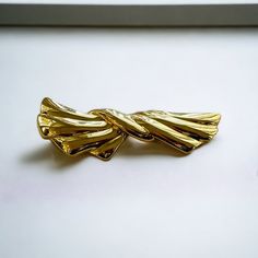 Vintage Trifari gold brooch.  This shiny brooch is 2.75 inches wide with a 1980's retro look.  The gold tone metal strands appear to flow in a bow design.  Marked Trifari and in great condition.  All jewelry comes in a gift box. Shop more of our vintage brooches go to https://www.Etsy.com/shop/Historicallyhers Gold Brooch Pins For Party, Elegant Gold Metal Brooches, Elegant Gold Metal Pins, Gold Metal Pins For Gifts, 80s Jewelry, Vintage Trifari, Gold Pin, Gold Brooches, Bow Design