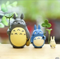 three toy figurines are standing next to each other on a table with plants in the background