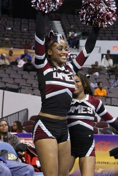 two cheerleaders in black and maroon outfits with pom poms on their heads