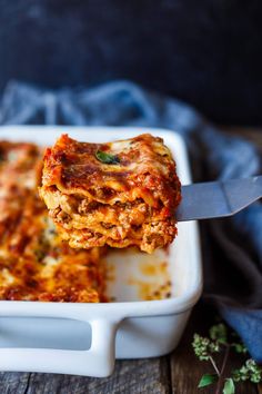 a close up of a piece of lasagna being lifted from a casserole dish