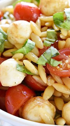 a white bowl filled with pasta salad and veggies on top of each other