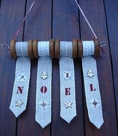 three neck ties hanging from a wooden pole with words on them that spell out noel