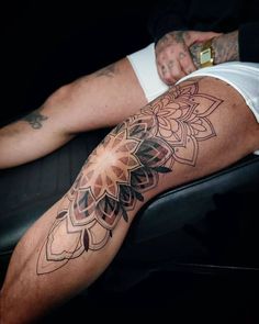 a man with a tattoo on his leg is sitting in a chair and holding onto the arm