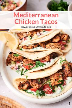 chicken tacos on a white plate with cilantro, tomatoes and lime wedges