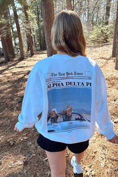 the back of a woman's white shirt with an image of two women walking in the woods