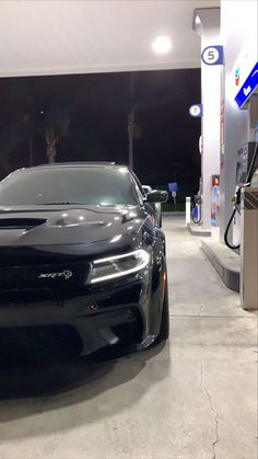 a black sports car is parked at a gas station in front of an electric charger