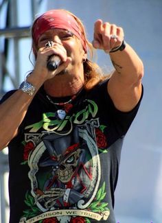 a man with a bandana on his head singing into a microphone