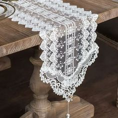 a white lace table runner sitting on top of a wooden table