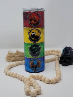 a wooden bead necklace next to a cup with four different colored beads on it