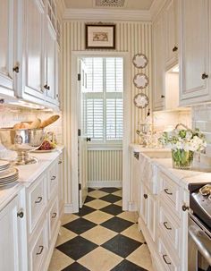 a kitchen with white cabinets and black and white checkered flooring on the walls