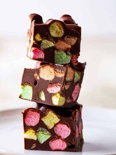 three pieces of chocolate on a white plate with colorful candies in the top and bottom