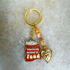 a gold keychain with a heart and some words on it that says happiness devoted to food