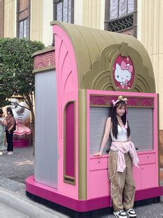 a woman standing next to a pink and gold kiosk