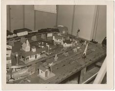 a black and white photo of a train track with toy houses on top of it