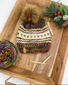 a knitted hat and yarn sitting on top of a wooden tray