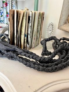 a black chain sitting on top of a white table next to a pile of papers