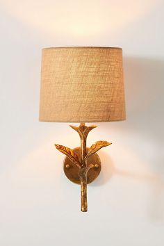 a wall mounted lamp with a bird on it's arm and a beige shade