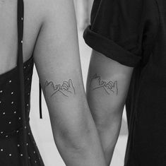 two people holding hands with tattoos on their arms