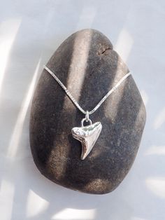 Often represented as symbols of strength, courage, and protection, a shark tooth can be a powerful amulet of individual expression. This silver shark tooth pendant necklace summons visions of prestige, strength, good fortune. Wear it proudly and invoke your power. ✦ DETAILS ✦ ✧ Mano (mah NO) - shark. ✧ Sterling silver shark tooth. ✧ Sterling silver chain. ✧ All Ke Aloha Jewelry pieces come packaged thoughtfully, beautifully, and ready for gift giving. ✧ Unless otherwise noted in the listing description, all pieces are sold individually. Photos with models/multiple pieces are for style inspiration only. ✦ OTHER NECKLACES SOLD SEPARATELY ✦ Shark Tooth Necklace Aesthetic, How To Make Shark Tooth Necklace, Sand Tiger Shark Tooth Necklace, Silver Shark Tooth Necklace, Shark Teeth Jewelry, Shark Jewelry, Silver Shark, Shark Tooth Pendant, Shark Necklace