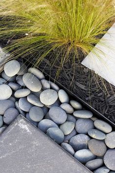 some rocks and grass in a black planter