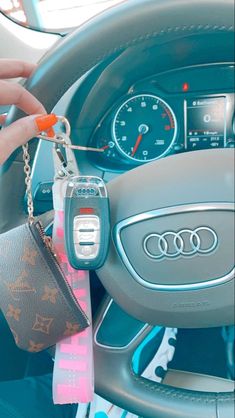 a hand holding a car key chain with an audi tag attached to the steering wheel