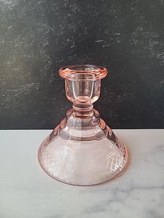 a glass candle holder sitting on top of a white marble counter next to a black wall