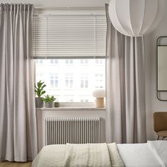 a bed sitting under a window next to a radiator in a room with white walls