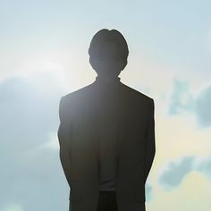 the silhouette of a man in a suit is shown against a blue sky with clouds