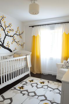 a baby's room with yellow drapes on the window and a tree painted on the wall