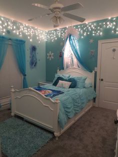 a bedroom decorated in blue and white with lights on the ceiling