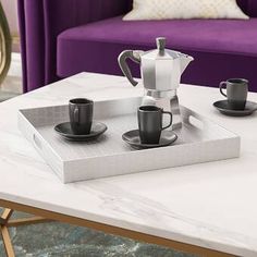 a tray with coffee cups on it sitting on a table in front of a purple couch