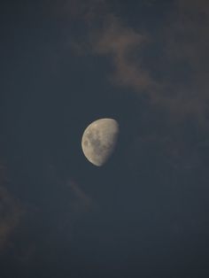 the moon is seen through some clouds on a dark night in this image, it appears to be half - full