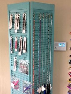 a blue display case with lots of necklaces hanging from it's sides and some cards attached to the back