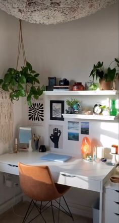 a white desk topped with a laptop computer next to a plant hanging from the ceiling