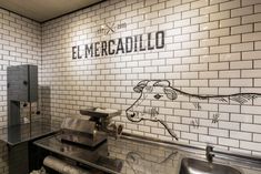 a restaurant with white brick walls and stainless steel sinks in front of the wall is a drawing of a cow