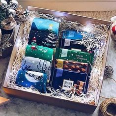 a box filled with assorted holiday gifts on top of a table next to christmas decorations